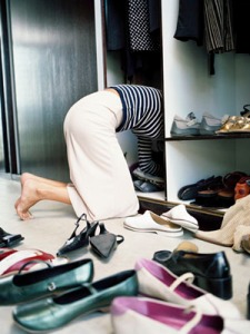 Woman on knees searching through shoes in wardrobe